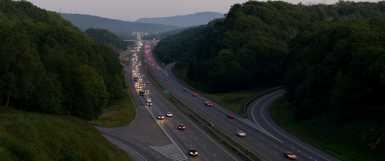 Interstate 49 corridor running through green Ozark hills at dusk