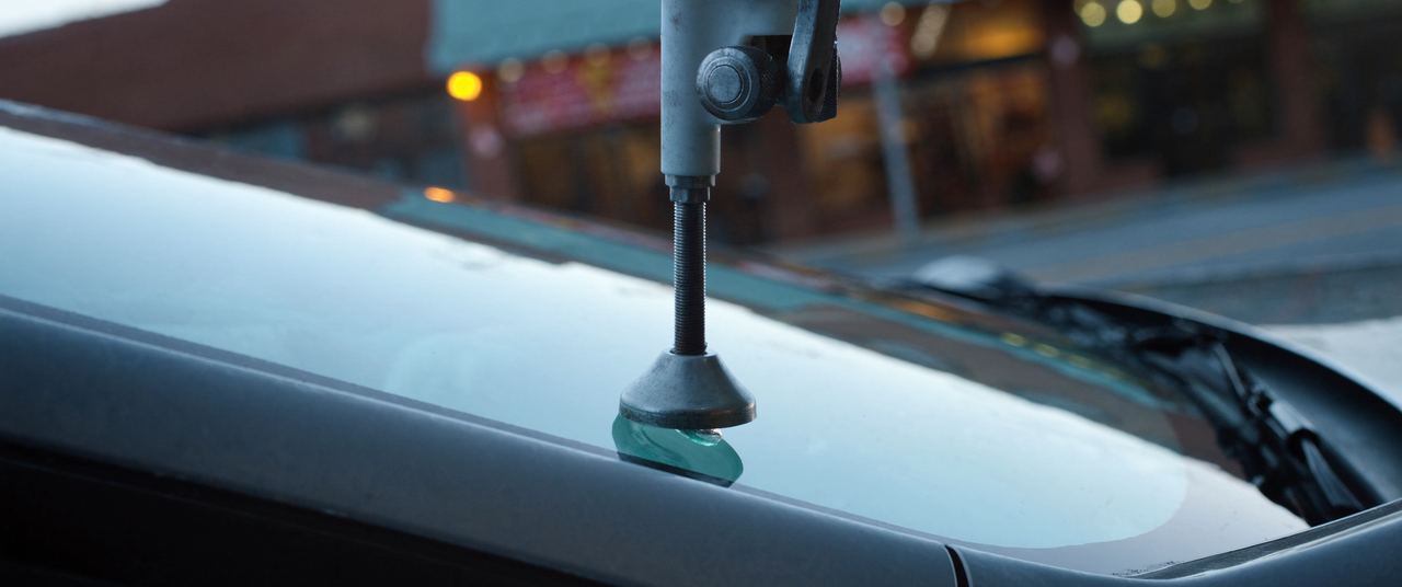Resin injection bridge tool clamped over a small rock chip in a windshield