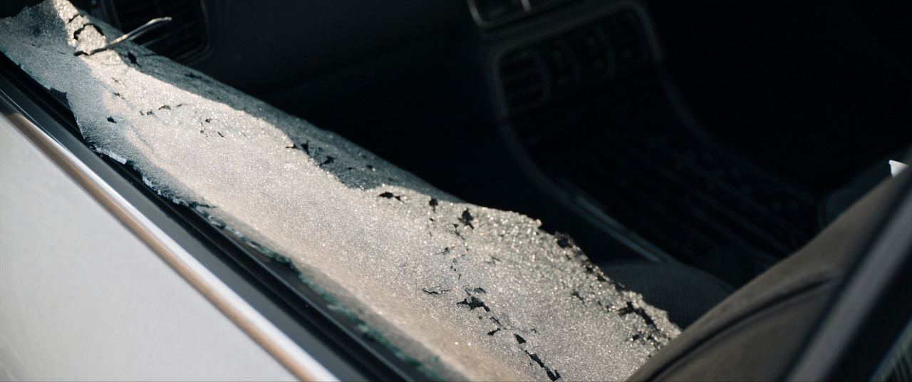 Tempered car side window shattered into small safety cubes across a seat and door sill