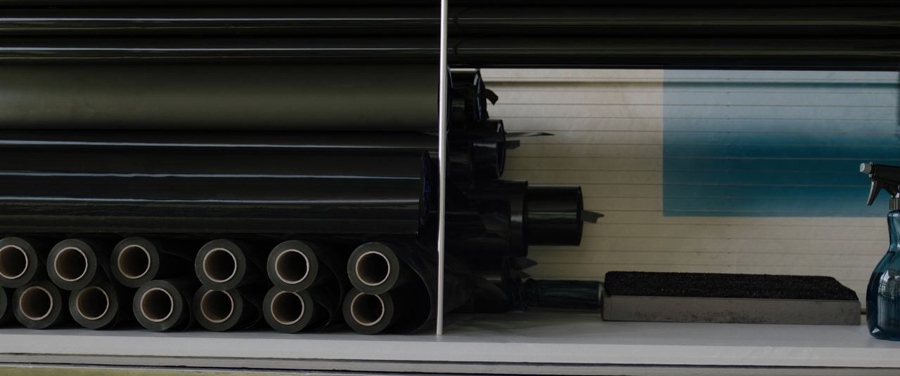 Rolls of automotive window tint film on a workshop shelf with squeegee and spray bottle